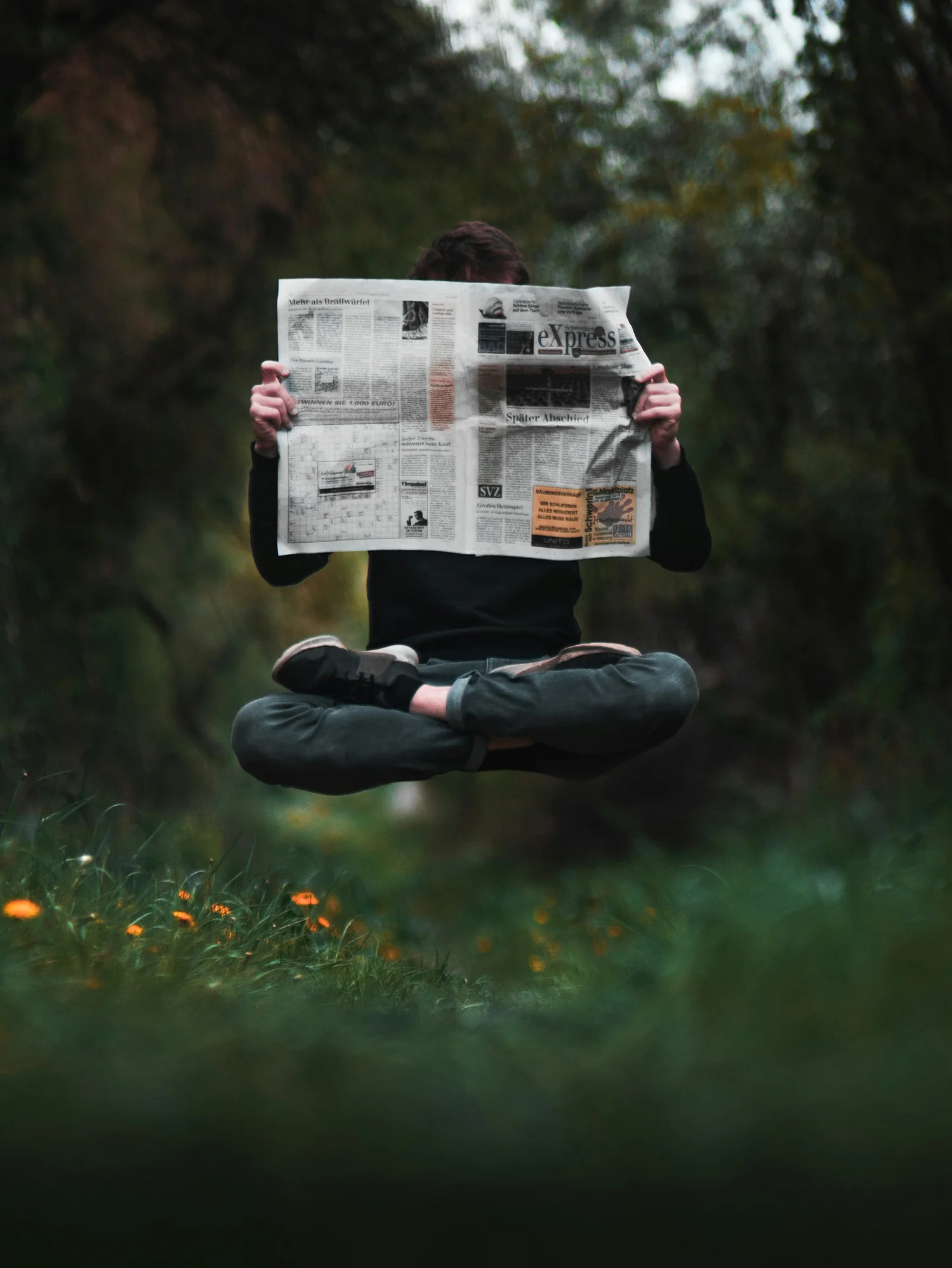 Eine Person schwebt im Wald und liest eine Zeitung. Sinnbild für Aktuelles von Kohli Treuhand GmbH in Spiez.